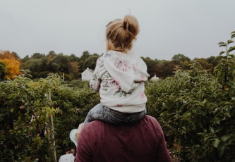 Adoptive daughter carried by her father on his shoulders
