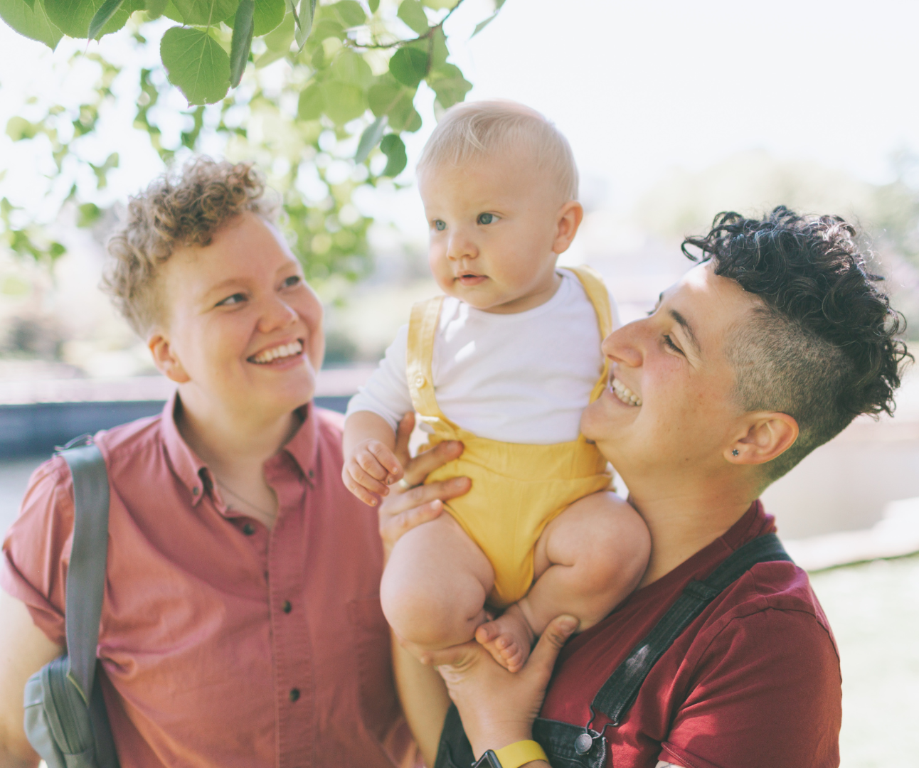 Lesbian couple carrying their baby and smiling