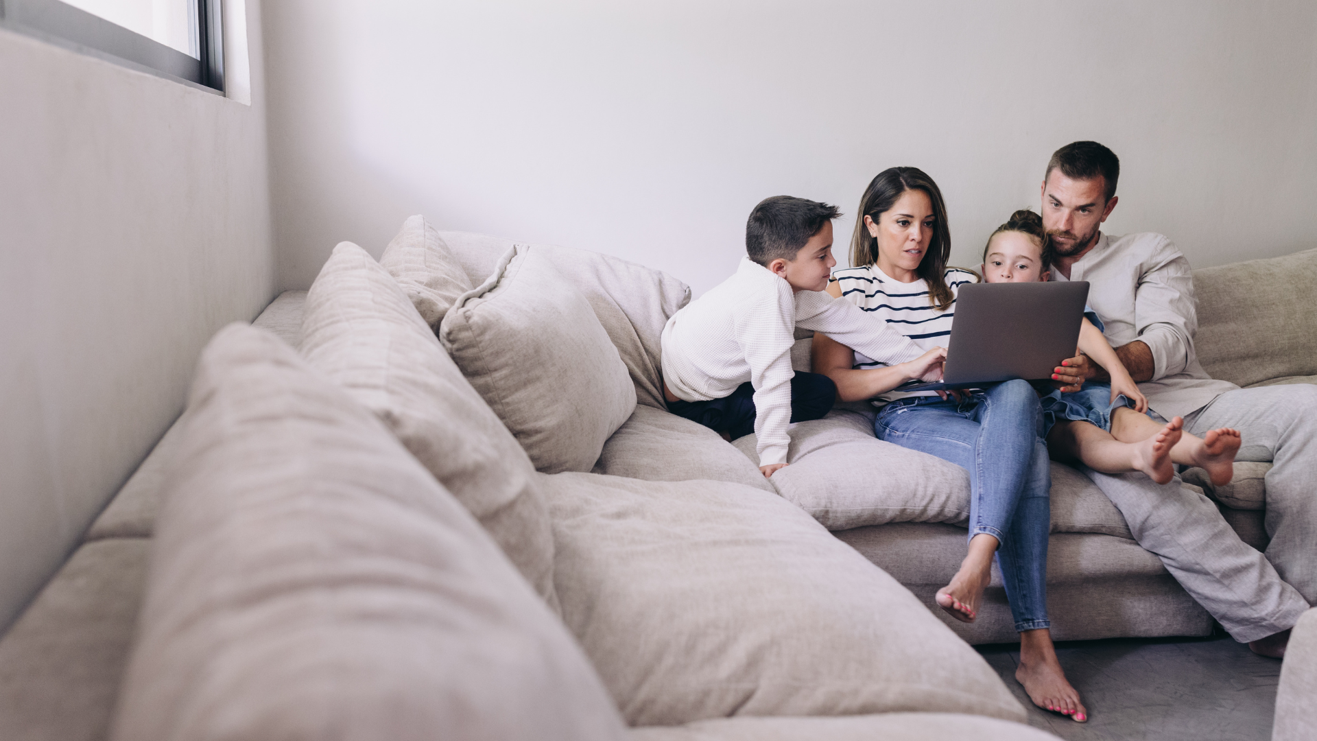 Family sat on sofa looking at laptop
